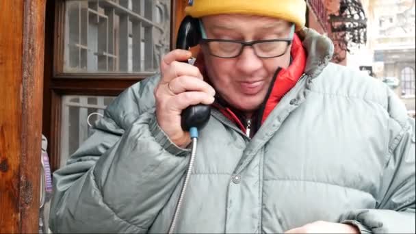付费电话 成年男子在街上的公共电话亭里感情用事地打电话 — 图库视频影像