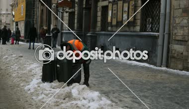 Lviv, Ukrayna, Ocak 2019: - kapıcı temizler çöp bir çöp bidonuna kışın şehir merkezinde bir sokakta.