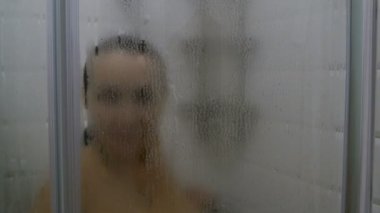 Banyo iç. Yetişkin kadın beyaz elbise buharlı cam ile kabinde duş alır. Modern banyo.