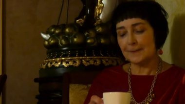 Zarif yaşlı kadın yalnız bir fincan kahve restoran veya kafe ile oturma ve konfor gevşeme romantik alacakaranlık bir atmosfer var.