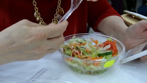 テーブルに座って大人のエレガントな女性白人民族性 プラスチックのフォークでおいしいサラダを食べて — ストック動画