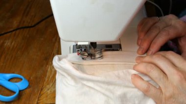 Terziliğin işleyişi, yaşlı terzinin elleri dikiş makinesine dikiş iğnesi, düğümleyici ve pres aletleri dikiyor. Küçük ev işi konsepti.