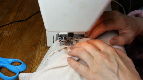 仕立て作業の工程では 縫製機に針 ルーパー プレス機で高齢者のシームレスな縫製の手が服を縫います 小規模住宅事業のコンセプト — ストック動画