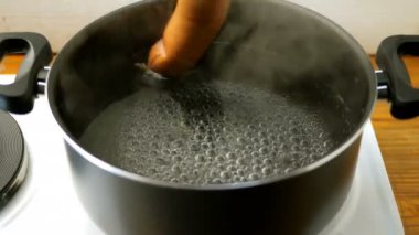 Ev yapımı yemek. Sosis aşağı ve elektrikli soba üzerinde kaynar su açık bir tava içinde haşlanmış vardır. Su kabarcığı.