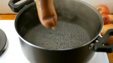 Ev yapımı yemek. Sosis aşağı ve elektrikli soba üzerinde kaynar su açık bir tava içinde haşlanmış vardır. Su kabarcığı.
