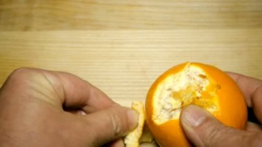 İnsan elleri ahşap masanın üzerine sulu portakal soyma. Kavram sağlıklı vejetaryen gıda. Close.