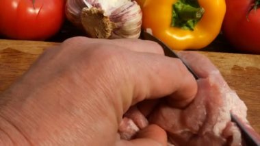 Çiğ et biftek ahşap bir kesme tahtası üzerinde domuz eti veya sığır eti büyük bir parça kesilir. Sebzeler: domates, tatlı biber, sarımsak. Close.