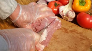 Çiğ et biftek ahşap bir kesme tahtası üzerinde domuz eti veya sığır eti büyük bir parça kesilir. Sebzeler: domates, tatlı biber, sarımsak. Close.