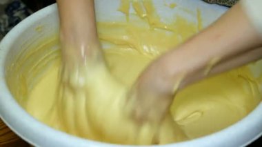 Ev yapımı yemekler pişirmek. Kadın fırıncı şiddetle mutfakta büyük bir kase içinde elleriyle hamur yoğuruyor. Close.