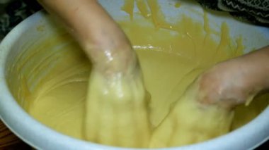 Ev yapımı yemekler pişirmek. Kadın fırıncı şiddetle mutfakta büyük bir kase içinde elleriyle hamur yoğuruyor. Close.