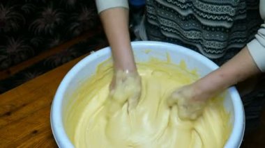 Ev yapımı yemekler pişirmek. Kadın fırıncı şiddetle mutfakta büyük bir kase içinde elleriyle hamur yoğuruyor. Close.