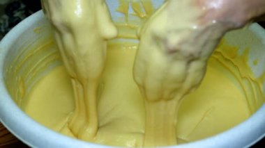 Ev yapımı yemekler pişirmek. Kadın fırıncı şiddetle mutfakta büyük bir kase içinde elleriyle hamur yoğuruyor. Close.