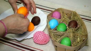 Tatil Paskalya için ev yapımı hazırlık. Kadın saman ile sepete renkli Paskalya yumurtaları koyar.