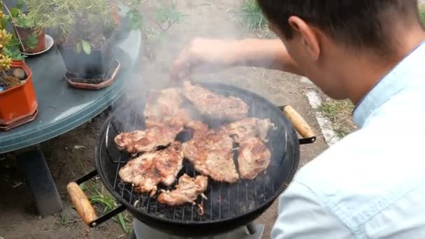 烤食品 肉牛排男人把大块美味的肉牛排 烤在烤肉上的煤 在金属炉架上的一个小户外烤架上 周末放松理念 — 图库视频影像