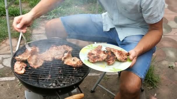 グリル料理 肉ステーキ男は 金属格子の上の小さな屋外グリルで バーベキューで石炭の上にロースト大きなおいしい肉ステーキをひっくり返します 週末のリラクゼーションコンセプト — ストック動画