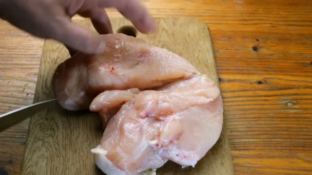 自家製料理 人間の手は 木製のまな板の上にバラバラに鶏の胸の切り身をカットします クローズ アップ — ストック動画