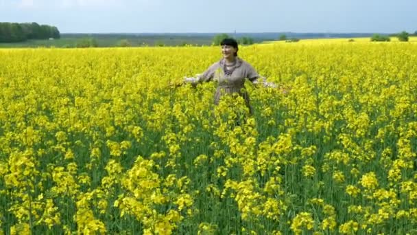 現場の女だ魅力的な美しいシニア女性の農民は 素朴なドレスで リラックスして油種レイプの開花分野を歩く 開花レイプ — ストック動画