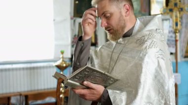 Kiev, Ukrayna, Mayıs 2019: - Genç rahip İncil'den bir dua okur ve Ukrayna'da bir kilisede dini bir ritüel yapar.