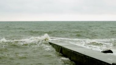 Karadeniz'de sörf yapın. Odessa yakınlarındaki Karadeniz'de küçük dalgalar dalgakıran ile bölünür. Kıyı şeridi, sıçrama, çökme, deniz köpüğü.