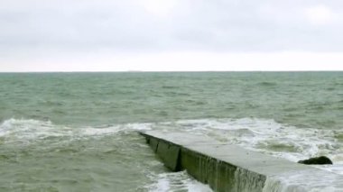 Karadeniz'de sörf yapın. Odessa yakınlarındaki Karadeniz'de küçük dalgalar dalgakıran ile bölünür. Kıyı şeridi, sıçrama, çökme, deniz köpüğü.