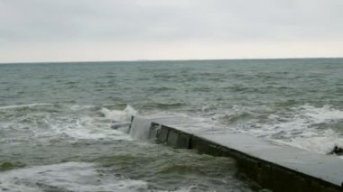 Karadeniz'de sörf yapın. Odessa yakınlarındaki Karadeniz'de küçük dalgalar dalgakıran ile bölünür. Kıyı şeridi, sıçrama, çökme, deniz köpüğü.