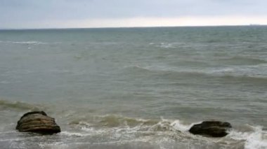 Karadeniz'de sörf yapın. Odessa yakınlarındaki Karadeniz'de kıyı taşlarında küçük dalgalar kırıldı. Kıyı şeridi, sıçrama, çökme, deniz köpüğü.