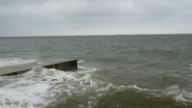 Karadeniz'de sörf yapın. Odessa yakınlarındaki Karadeniz'de küçük dalgalar dalgakıran ile bölünür. Kıyı şeridi, sıçrama, çökme, deniz köpüğü.