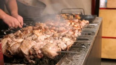 İnsan elleri, metal bir barbeküde şişüzerine bağlanmış büyük et parçalarından şiş kebapları veya şişlikleri kızartın.