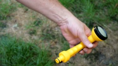 Ev bahçe. İnsan elleri yeni yeşil kauçuk hortum içine sarı bir bahçe püskürtücü eklemek.