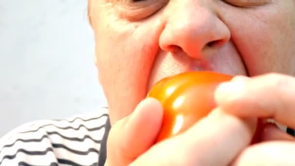 空腹の高齢者は速く 貪欲にジューシーな大きな赤いトマトを食べます クローズ アップ — ストック動画