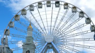 Yakın çekim büyük beyaz dönme dolap Kiev şehir döner, Ukrayna, mavi gökyüzü arka plan ve arka planda Ortodoks Kilisesi çan kulesi üzerinde Contractova meydanında.