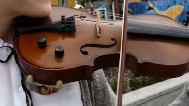 キエフ、ウクライナ、2019年6月:ブスカーは、広場の屋外でバイオリンで音楽を演奏します。街の通りでクラシック音楽を演奏する美少女. — ストック動画