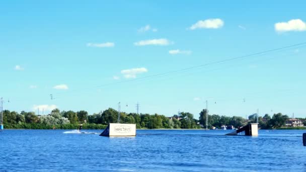 Kiev, Ucrania, julio de 2019: - Wakeboarder salta por la rampa o el trampolín en el tablero de vigilancia en el río Dnieper en el día de verano . — Vídeo de stock