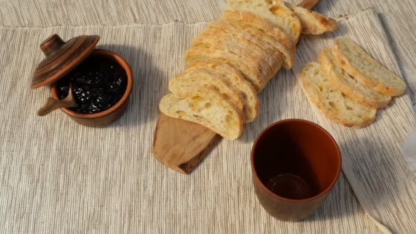 Lekker ontbijt. Vers brood met jam en melk. Melk wordt in een beker gegoten. Toast met fruit jam op servet. Evenwichtige voeding. Rustieke stijl. — Stockvideo