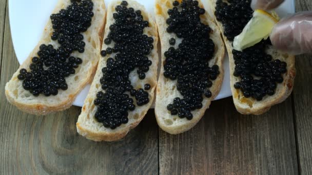 Preparación de sándwiches con caviar negro. El caviar de esturión negro se unta con un cuchillo de cocina en una rebanada de pan blanco. Deliciosas delicias culinarias. Comida de lujo caro . — Vídeos de Stock