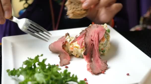 Leckeres Abendessen. Menschen essen traditionellen Salat für slawische Völker olivier oder Salat mit Gemüse und Fleisch in Café oder Restaurant von weißem Teller. — Stockvideo