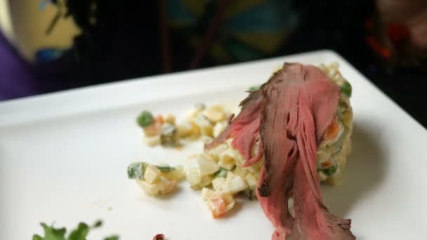 Smakelijk diner. Menselijk eten traditionele salade voor Slavische volkeren Olivier of salade met groenten en vlees in café of restaurant van witte plaat. — Stockvideo