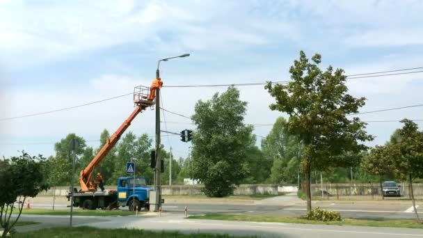 Reparatie van stadsverlichting. Werknemer Electric verandert een lamp of reparaties apparatuur op een lantaarnpaal naast de weg. Met een truck kraan. Totaalplan. — Stockvideo