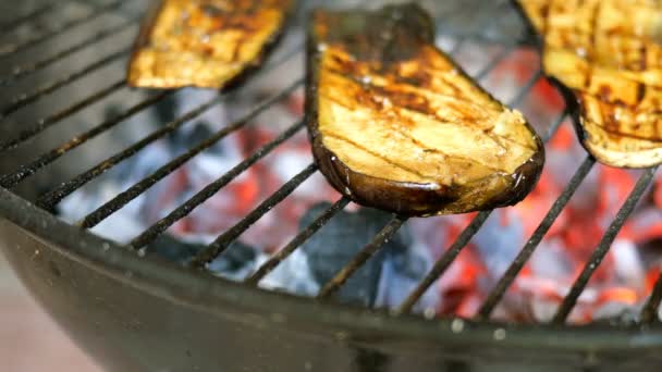 Skivade aubergine biffar är stekt på en grill eller grill och vände med kök tång. Ena sidan av auberväxten brann. Närbild. — Stockvideo