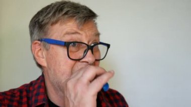 Eksantrik kıdemli adam, gri Saç ile bir balon şişirilir, sonra deldi ve patlar ve yüksek sesle çığlıklar, onun dişsiz ağzını geniş açarak. Yakın çekim portre.