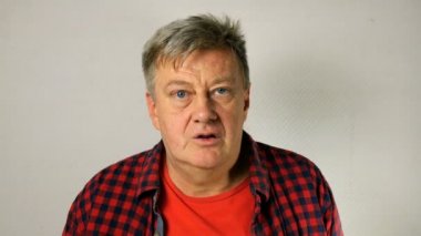 Yakışıklı adam, gri saçlı, sıradan kıyafetler içinde üst düzey yetişkin, olumlu bir şekilde başını savuruyor ve birine evet ve tamam diyor. Açık gri arka planda. Close.