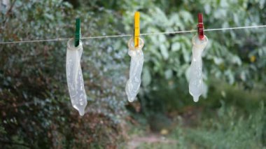 Şeffaf lateks prezervatif evin arka bahçesinde clothesline asmak, clothespins ile bağlı ve hafif esinti salıncak. Belki de tekrar kullanılmak üzere yıkandılar. Açık havada.