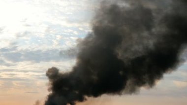 Gökyüzündeki siyah duman sütunu. Bu yangın, yangın enkaz, fabrika boru suã§u veya patlama yakar. Duman döner ve rüzgar tarafından taşınır. Gün batımına ve bulutlara karşı. Açık havada.