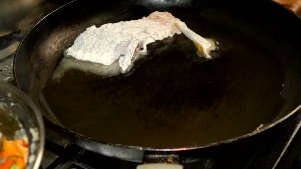 Cozinha caseira. A carpa de peixe de rio, cortada em pedaços, frita-se na panela no óleo de cozinha. Close-up . — Vídeo de Stock