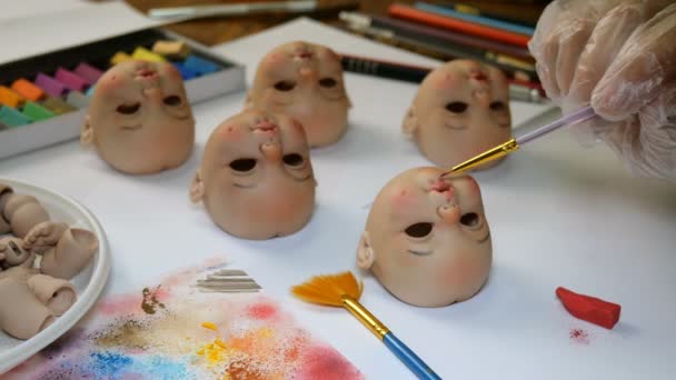 Making dolls. Master painter carefully paints lips of blank for doll with thin brush. Concept of combining work and hobbies. — Stock Video