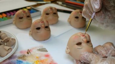 Bebek yapıyorum. Usta ressam dikkatle ince fırça ile bebek için boş dudakları boyar. İş ve hobileri birleştirme kavramı.