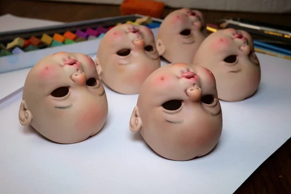 Making dolls. Heads of dolls are on the table by artist doll mas