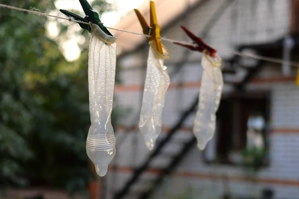 Transparent latex condoms hang on clothesline in backyard of hou — Stock Photo, Image