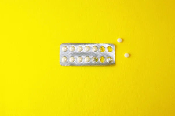 Blister meio vazio com comprimidos brancos jaz em um backgroun amarelo — Fotografia de Stock