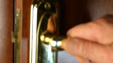 İnsan elleri kapıyı kapatır ve anahtarla kilitler. Kapananı doğrulayacak metal kolu çekti. Yakın plan..